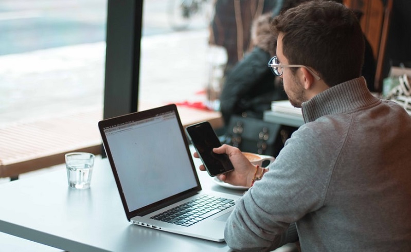 homme dans un café sur son portable et ordinateur