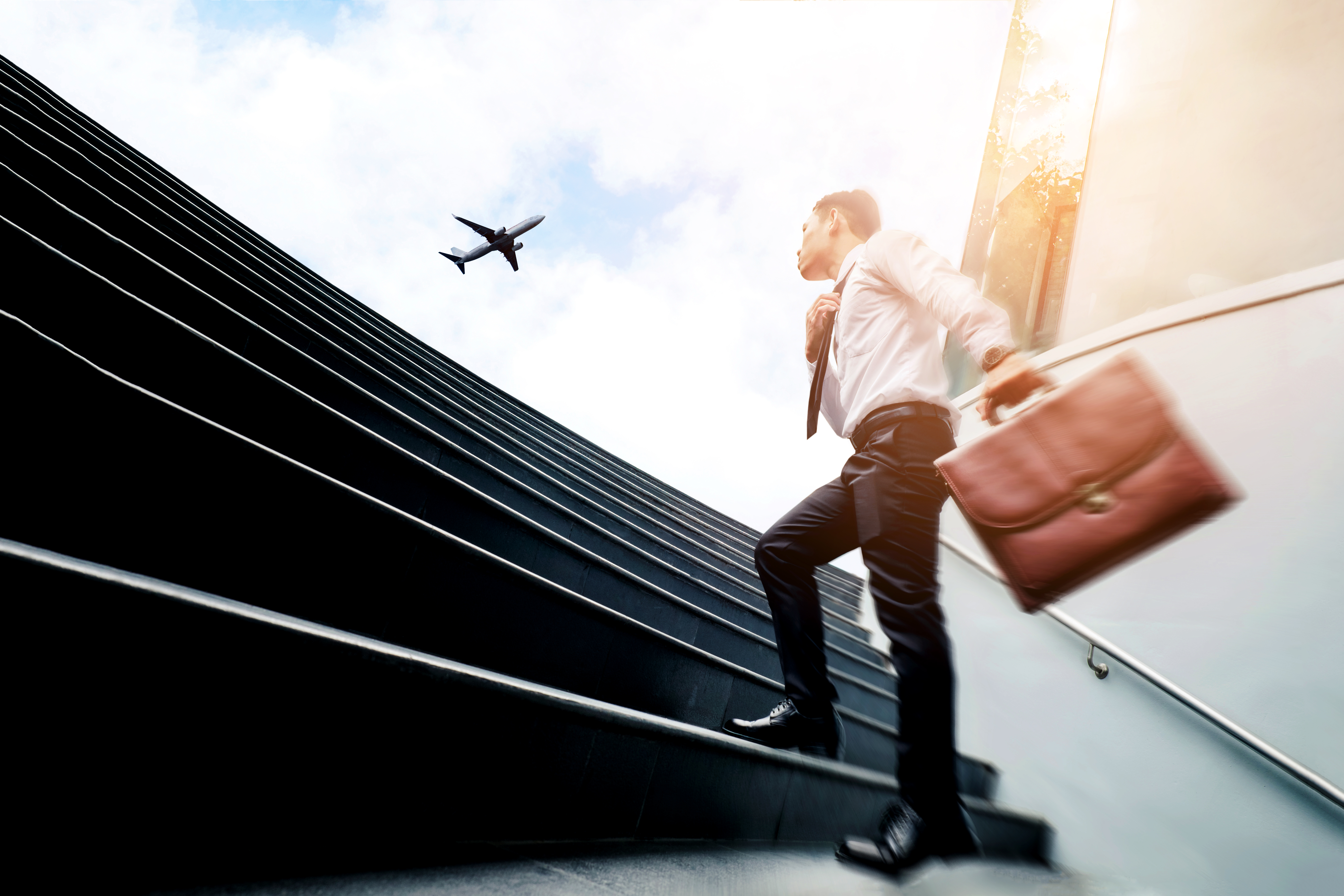 Homme avec une valise dans l'escalier avec un avion en arrière plan